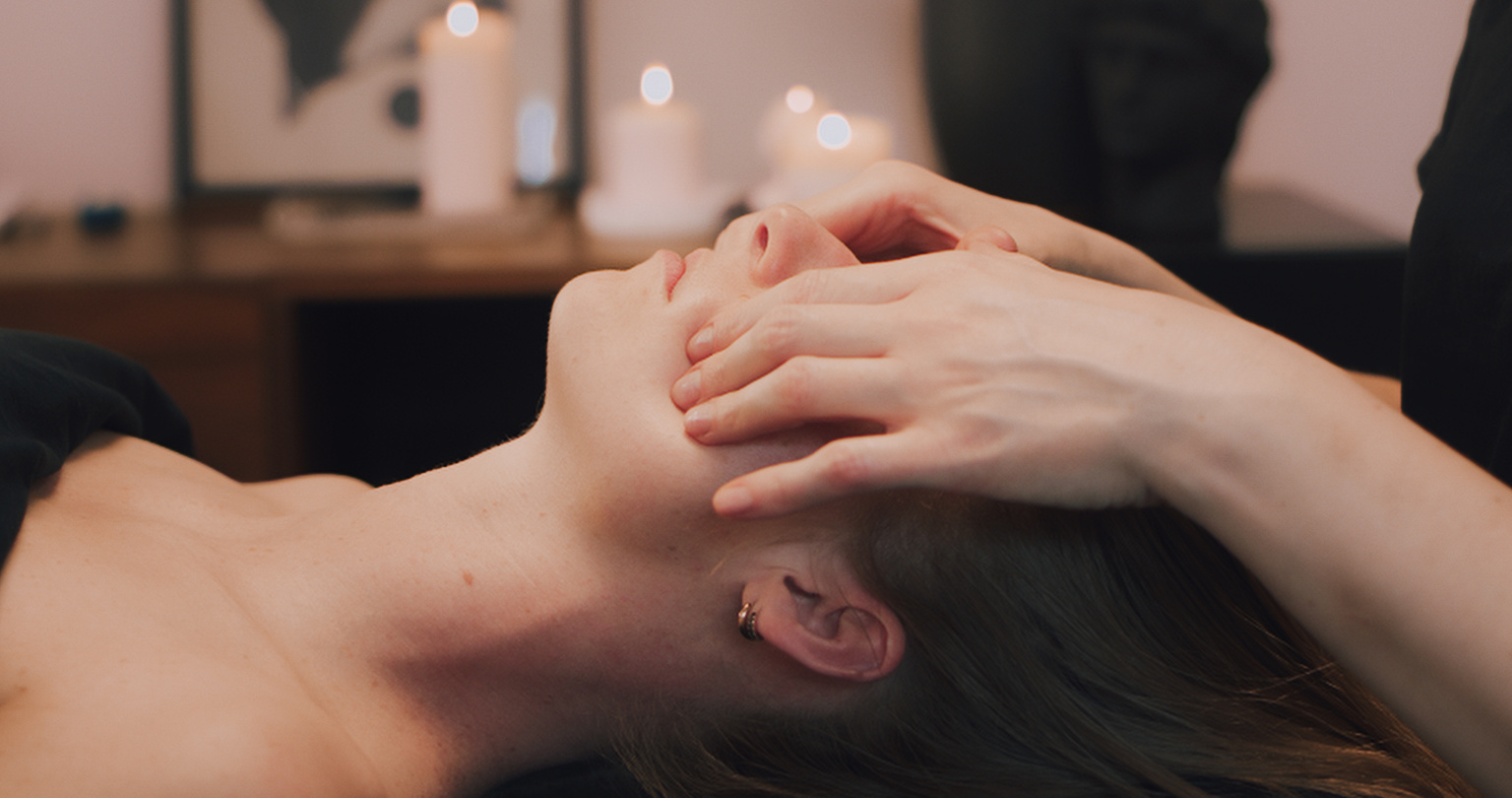 Kobido facial massage. The beautician is massaging the client's head.