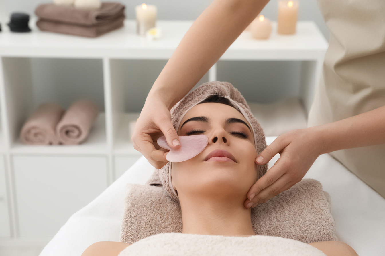 Young Woman Receiving Facial Massage with Gua Sha Tool in Beauty